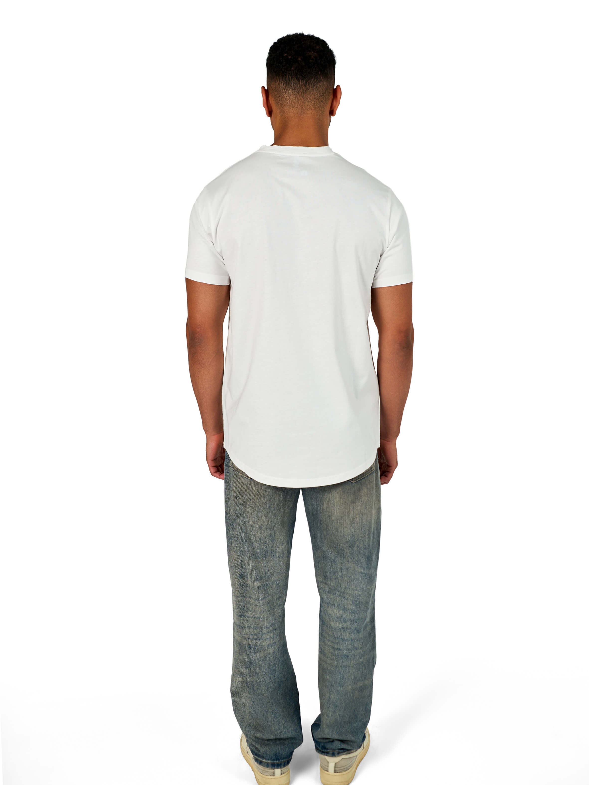 A male model wearing a white raw-edged cotton crew neck t-shirt with short sleeves and a rounded hem.