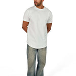 A male model wearing a white raw-edged cotton crew neck t-shirt with short sleeves and a rounded hem.