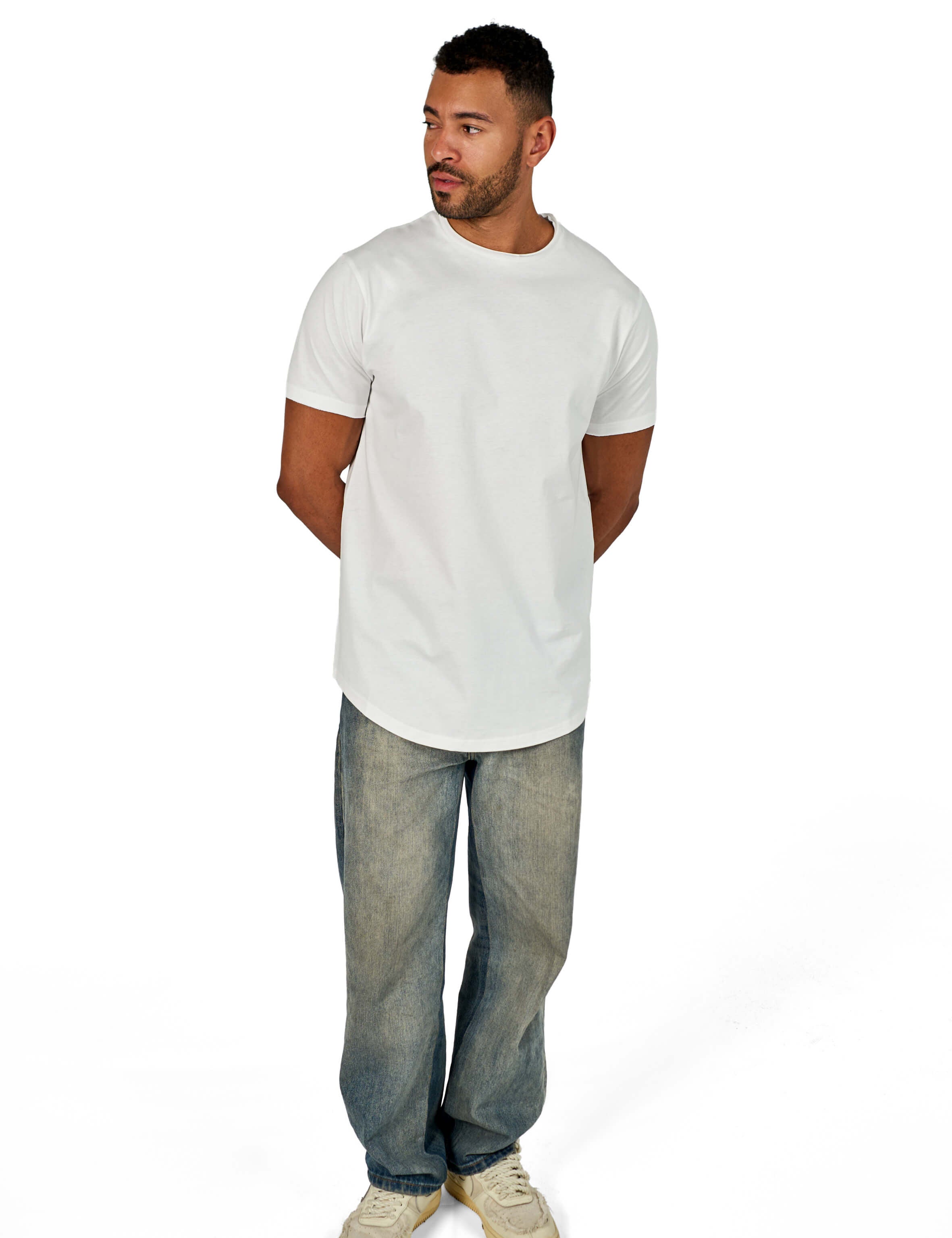 A male model wearing a white raw-edged cotton crew neck t-shirt with short sleeves and a rounded hem.