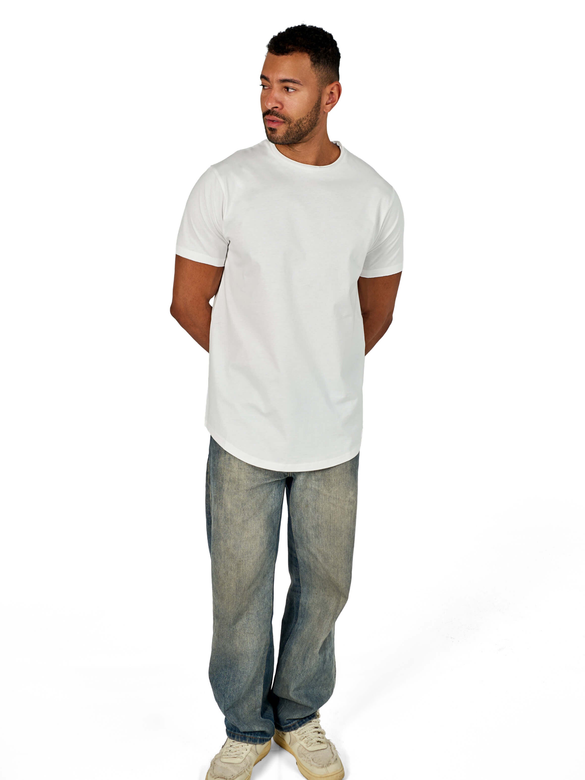 A male model wearing a white raw-edged cotton crew neck t-shirt with short sleeves and a rounded hem.