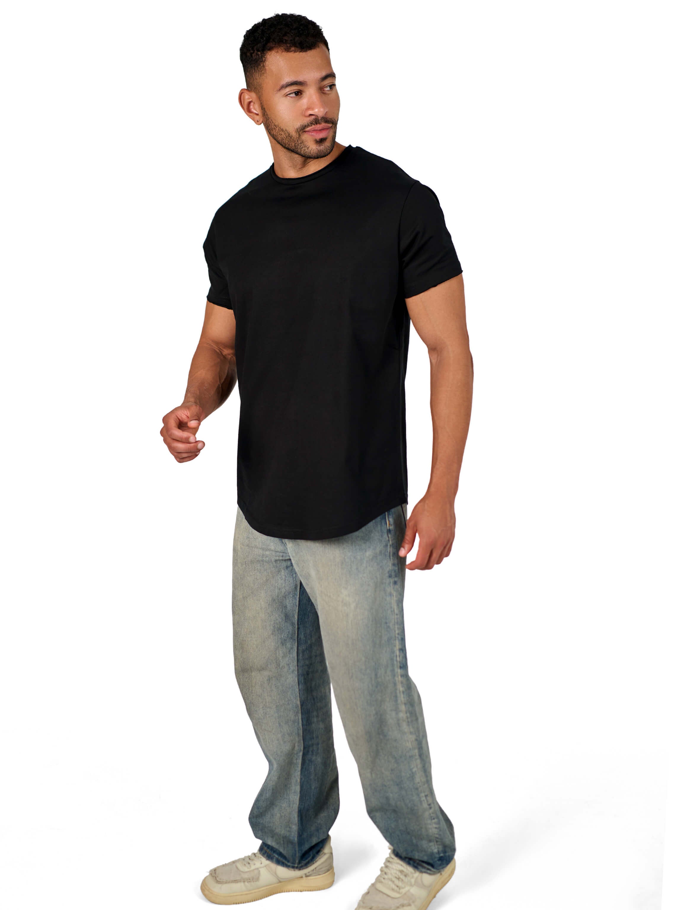 A male model wearing a black raw-edged cotton crew neck t-shirt with short sleeves and a rounded hem.