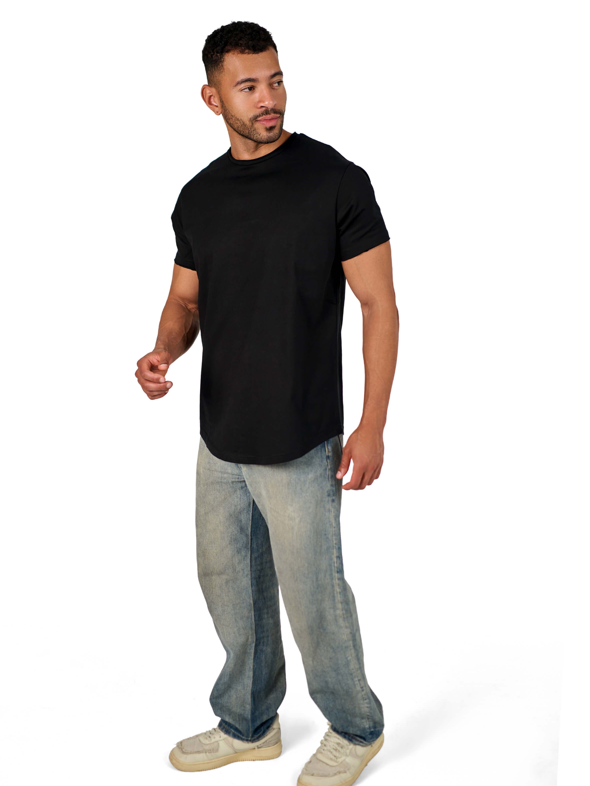 A male model wearing a black raw-edged cotton crew neck t-shirt with short sleeves and a rounded hem.
