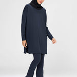Woman wearing a long-sleeve navy modest loose sports activewear top with a hijab on a white background, branded 'LUXE'.