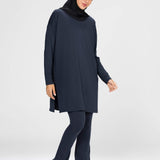 Woman wearing a long-sleeve navy modest loose sports activewear top with a hijab on a white background, branded 'LUXE'.