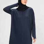 Woman wearing a long-sleeve navy modest loose sports activewear top with a hijab on a white background, branded 'LUXE'.