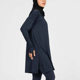 Woman wearing a long-sleeve navy modest loose sports activewear top with a hijab on a white background, branded 'LUXE'.