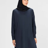 Woman wearing a long-sleeve navy modest loose sports activewear top with a hijab on a white background, branded 'LUXE'.