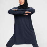 Woman wearing a long-sleeve navy modest loose sports activewear top with a hijab on a white background, branded 'LUXE'.