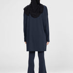Woman wearing a long-sleeve navy modest loose sports activewear top with a hijab on a white background, branded 'LUXE'.