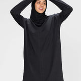Woman wearing a long-sleeve black modest loose sports activewear top with a hijab on a white background, branded 'LUXE'.